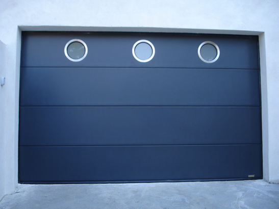 Porte de garage sectionnelle bleue foncée avec hublots ronds